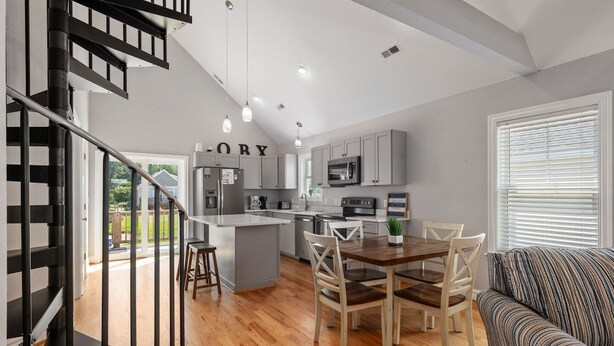 A modern kitchen with grey cabinets, a central island, and a dining area with wooden chairs.