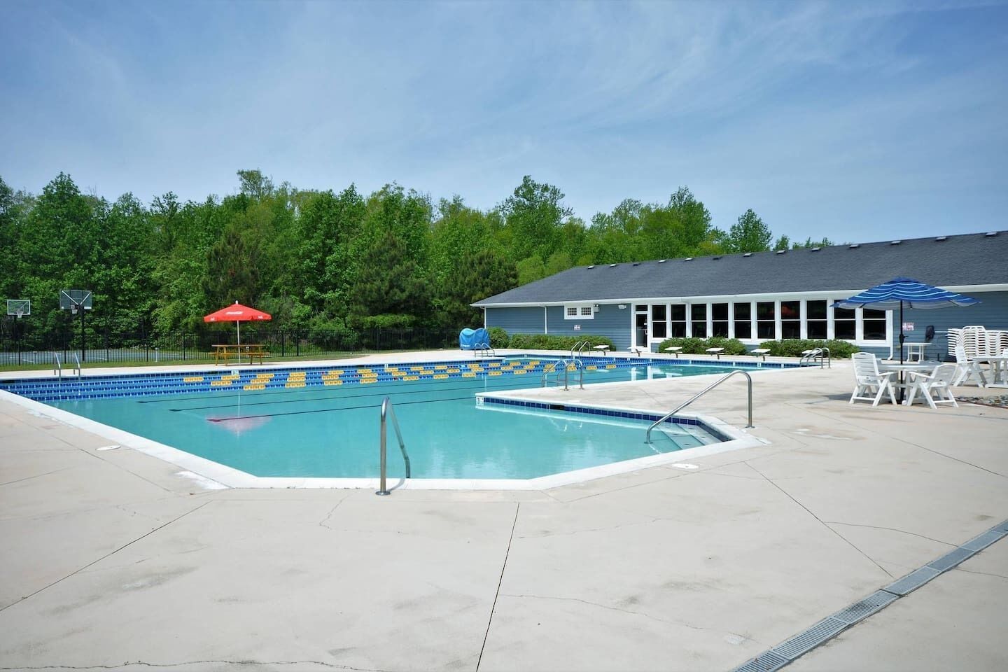A swimming pool with lane dividers, a covered seating area, and a building in the background.