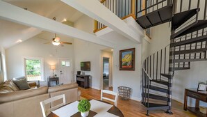 A spacious living area with a high ceiling, a staircase, and a dining area with a table and chairs. - OBX Cottages The Snead Cottage (Powells Point)