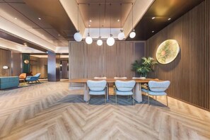 A modern dining area with a herringbone wood floor, a wooden table with four chairs, and a large wall-mounted light fixture.