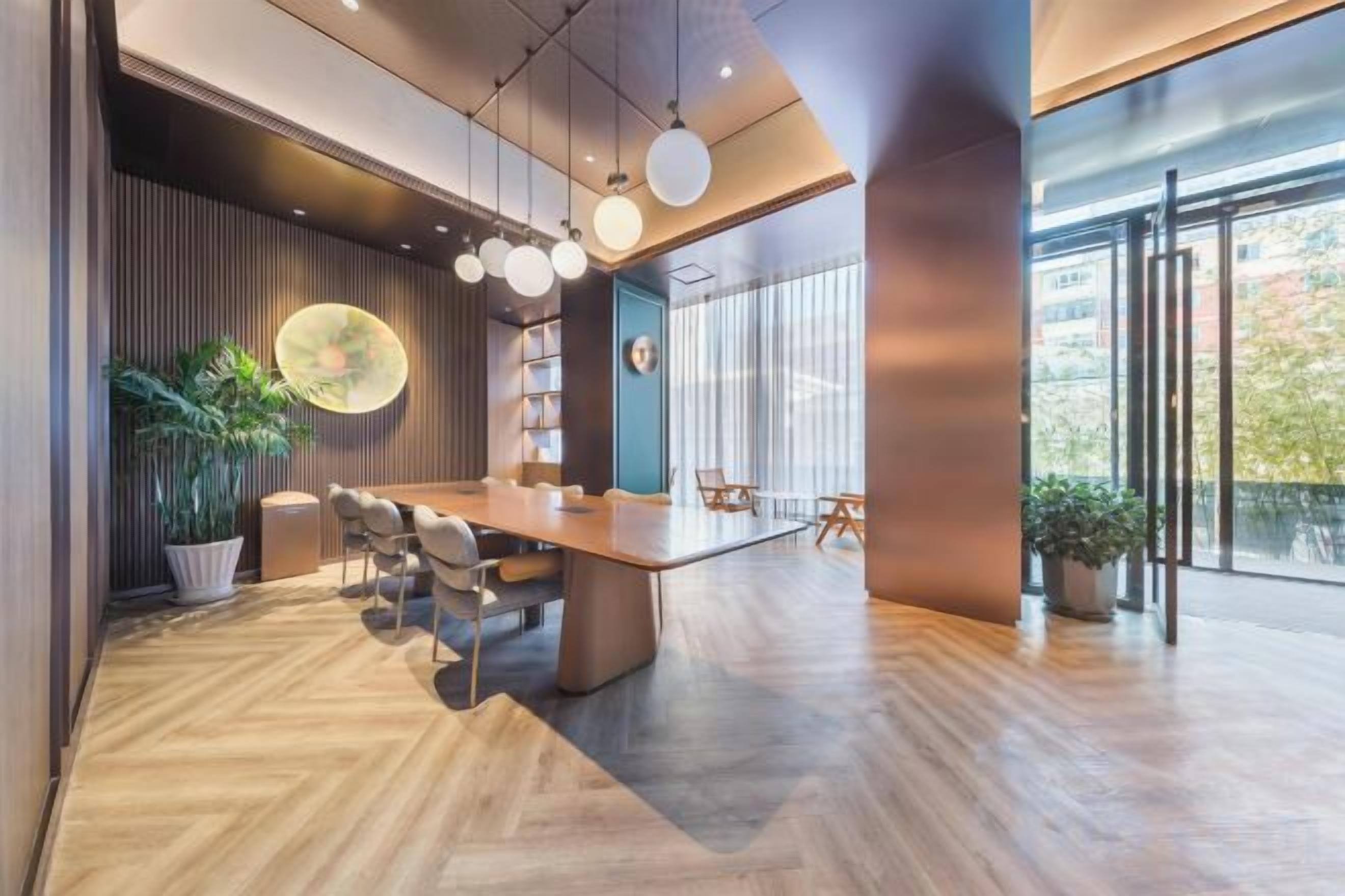 A modern conference room with a large table, chairs, and a potted plant.