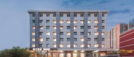 Un hotel de varios pisos con una entrada central y fachada plana.