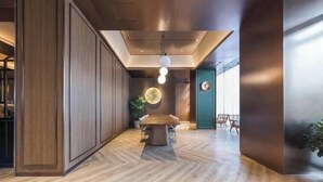 A modern interior with a herringbone wood floor, a central dining table, and a hanging light fixture.