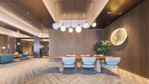 A modern conference room with a herringbone floor, a wooden table with four chairs, and a large potted plant.