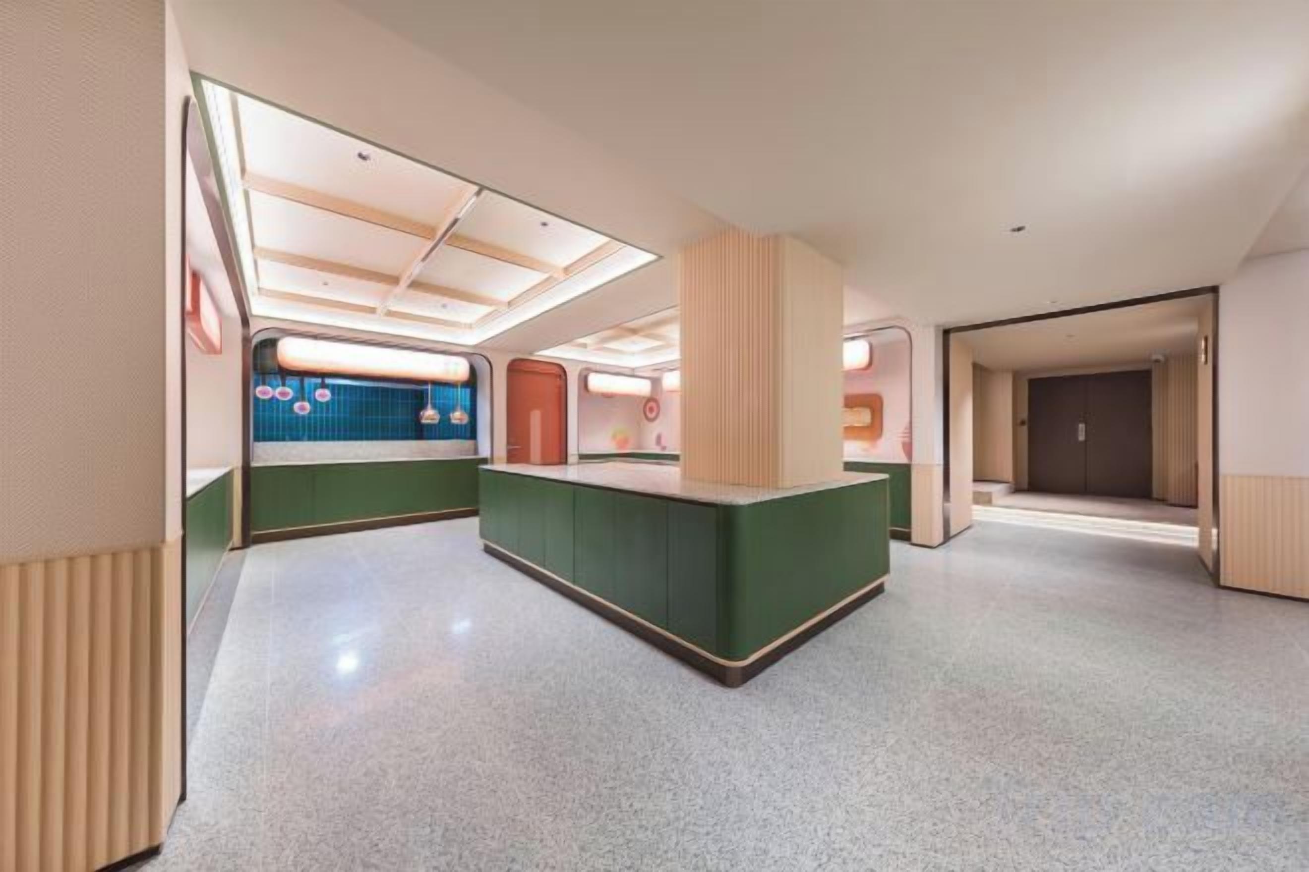 A modern hotel lobby with a reception desk, a waiting area, and a visible elevator.