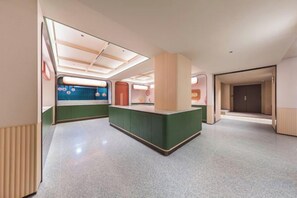 A modern hotel lobby with a reception desk, a waiting area, and a visible elevator. - Orange Hotel (Beijing West Railway Station South Square) (Beijing)