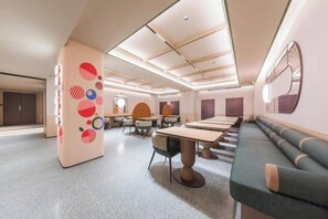 A modern hotel lobby with a long reception desk, seating area, and a decorative wall with abstract patterns. - Orange Hotel (Beijing West Railway Station South Square) (Beijing)