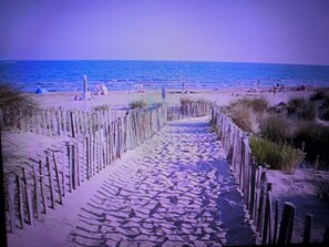 Une promenade en bord de mer, avec des poteaux en bois, et une plage de sable en arrière-plan.