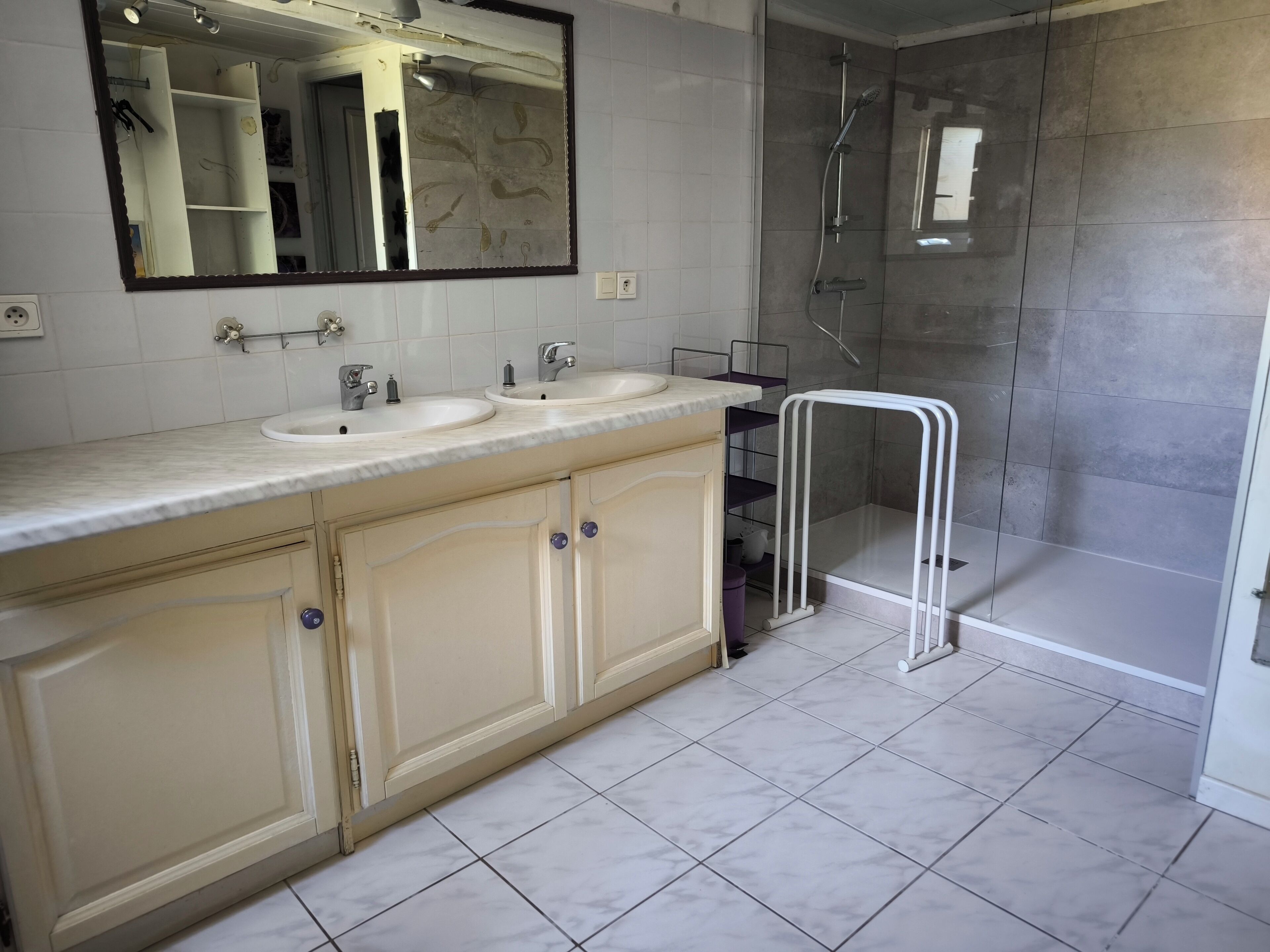 Un baño con dos lavamanos, un espejo y zona de ducha.