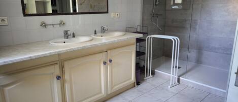 Un baño con dos lavamanos, un espejo y zona de ducha.