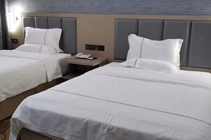 Habitación de hotel con dos camas, una mesita de noche y un teléfono en la pared.