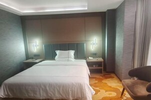 Habitación de hotel con cama, mesitas de noche, una silla y cabecera con iluminación integrada.