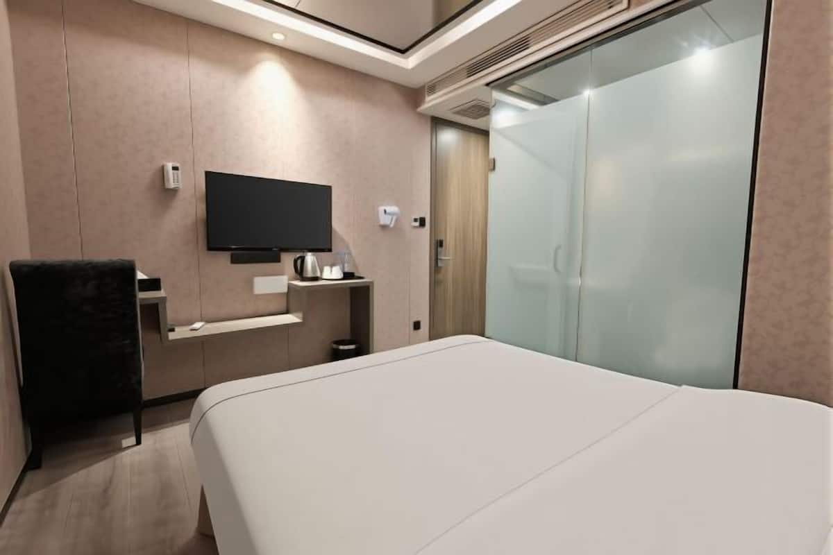 Una habitación de hotel con una cama, televisión, escritorio y silla.