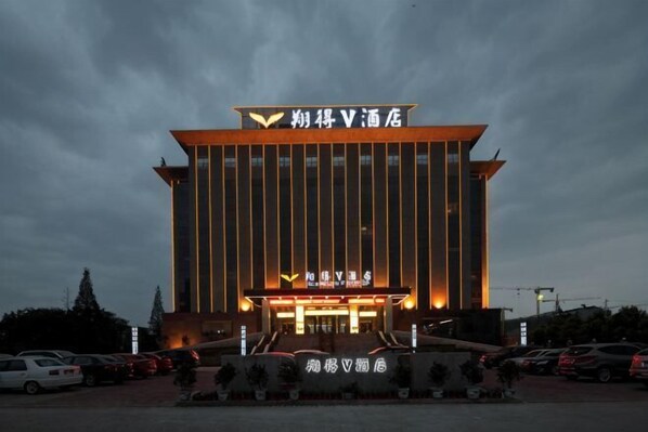 A hotel with a prominent sign, a large entrance, and a parking lot. - Xiang De V Hotel (Jianli)