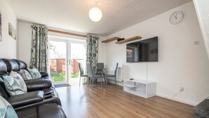 A living room with a leather sofa, a TV, and a dining area with chairs and a table.