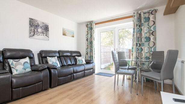 A living room with a leather sofa, a glass coffee table, and a dining area with chairs.