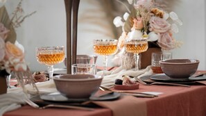A table set with clear glassware, a brown bowl, and a vase with flowers.