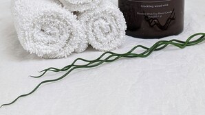 A candle labeled "ROSEMARY + LINEN" and rolled white towels. - Family & Friends HUGE House Dubai MALL Fast Ride (Dubai)
