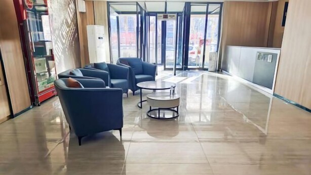 A lobby with a glass door entrance, a reception desk, and seating area with chairs and a small round table. - IU Hotel Yining Shanghai City (Yining City)