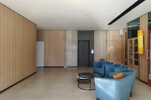 Een moderne lobby met een zithoek, een receptiebalie en een deur naar de liften.