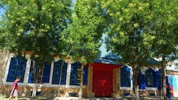 A building with a red door and blue windows, surrounded by trees.