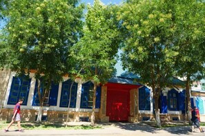 Un edificio con ventanas grandes y una puerta roja, rodeado de árboles.