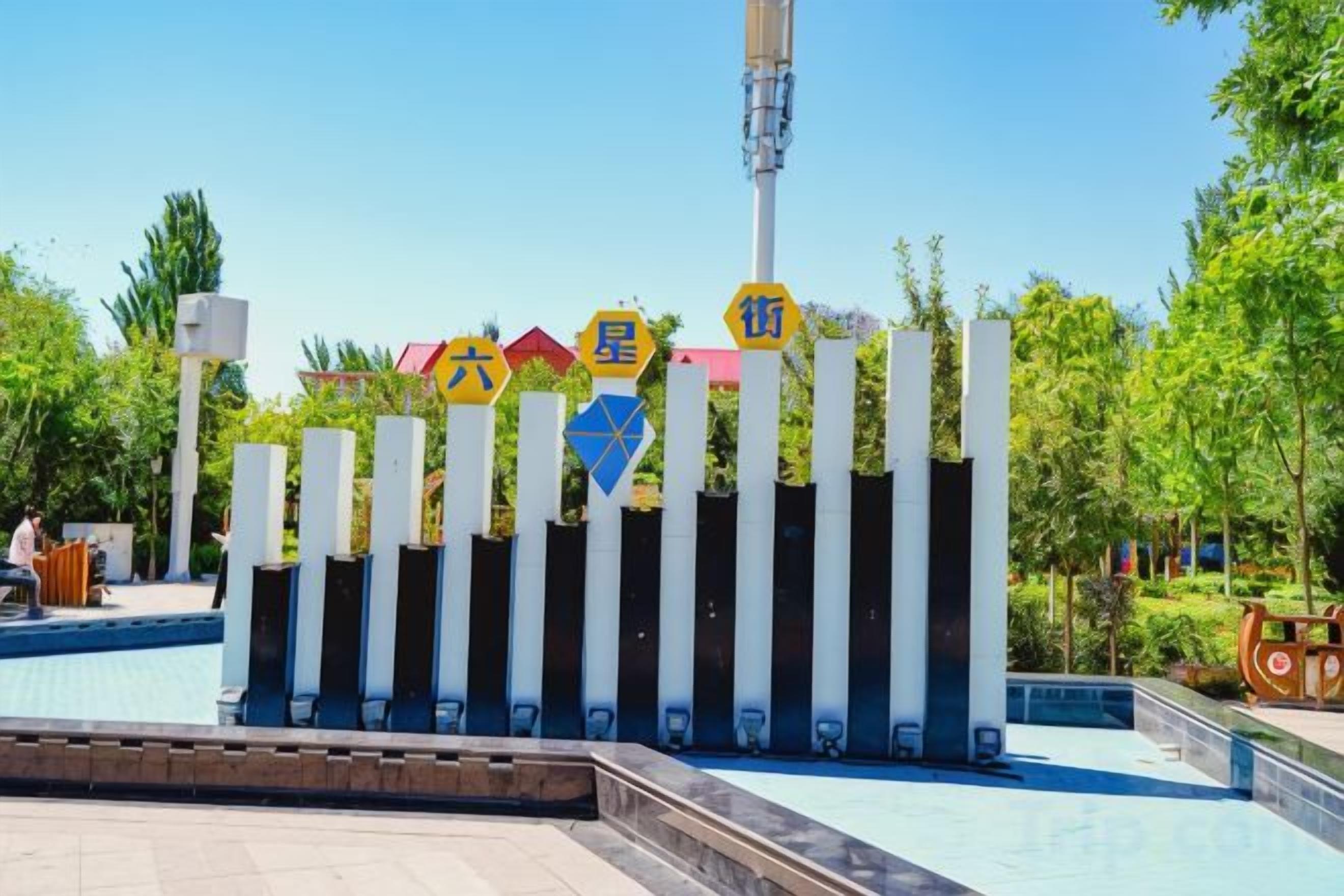 A sign with multiple symbols and text, a clear sky, and a pool area with a fence.