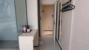 A hotel hallway with a reception desk, a coat rack, and a door leading to another room. - IU Hotel Yining Shanghai City (Yining City)