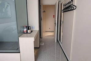 A hotel hallway with a reception desk, a coat rack, and a door leading to another room. - IU Hotel Yining Shanghai City (Yining City)