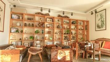 Una sala de estar con una amplia estantería de madera, diversas opciones de asientos que incluyen sofás y sillones, y una mesa de comedor.