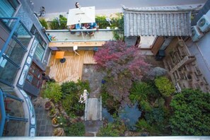 A courtyard with a wooden deck, potted plants, and a traditional tiled roof structure. - Longkan Yunding Courtyard Hotel (Dali City)
