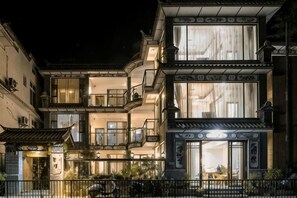 Un edificio de varios pisos con elementos arquitectónicos tradicionales, balcones y ventanas amplias.
