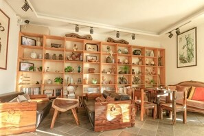 Een woonkamer met een grote houten boekenkast, verschillende zithoeken en een eettafel.