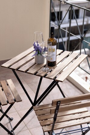 A wooden table with a bottle of wine and a glass on it, set against a metal railing. - Terminal Square Suites (Markopoulo Mesogaias)