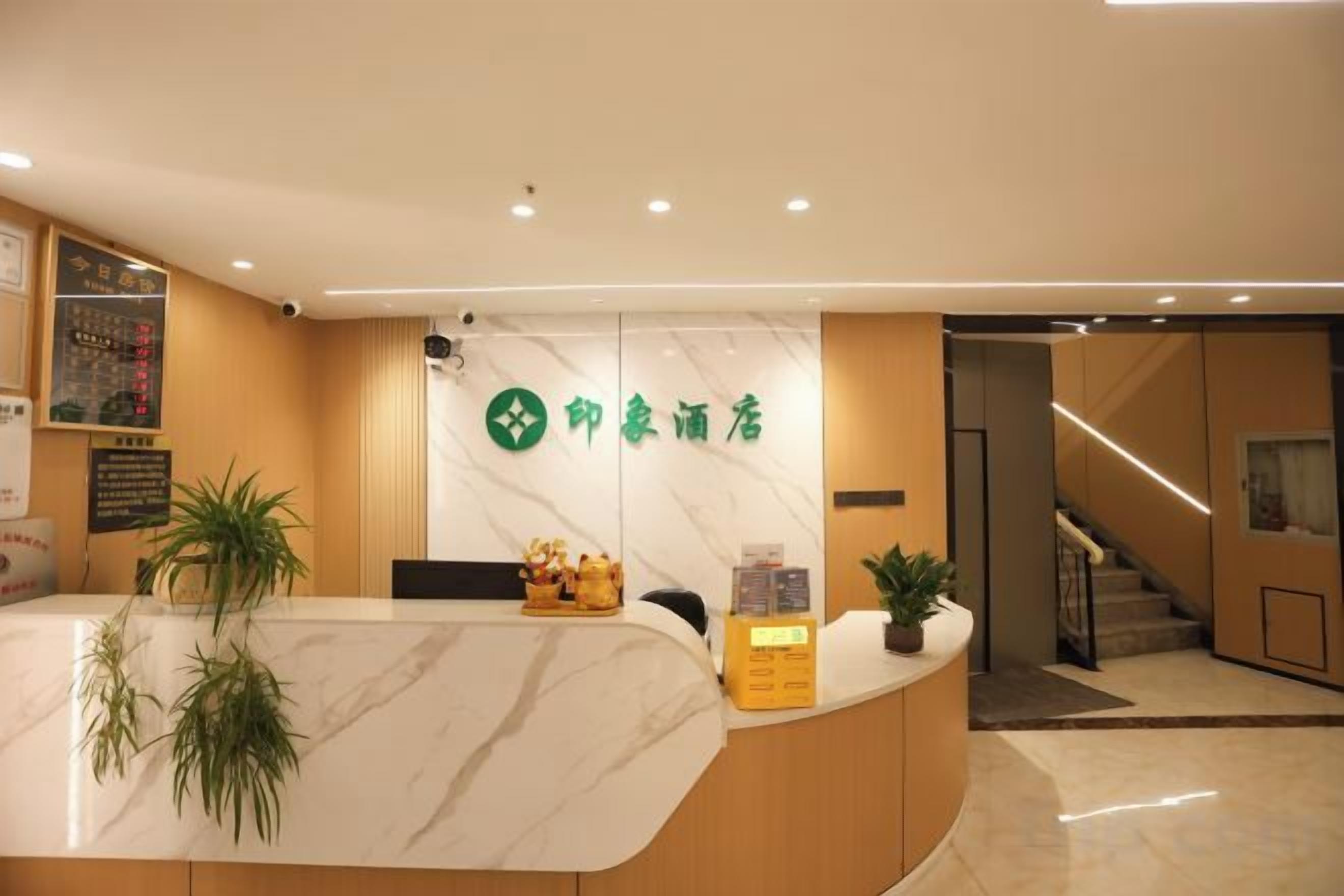 A hotel reception area with a marble counter, a green logo, and a staircase in the background.
