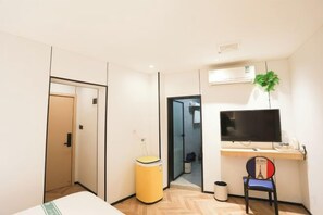 A hotel room with a bed, a desk with a computer, a chair, a trash bin, and a television. - Shanghai Xinnuo Hotel (Shanghai)