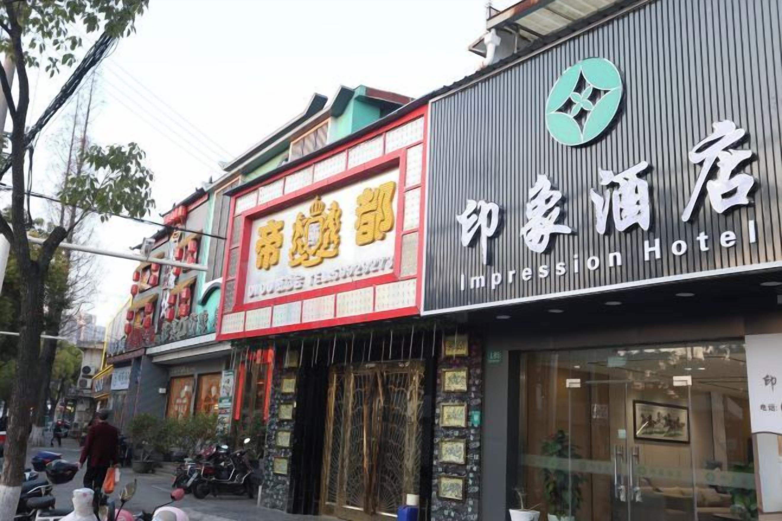Un hotel con un letrero destacado que dice 'Impression Hotel' y otro letrero que dice 'House of Beauty'.