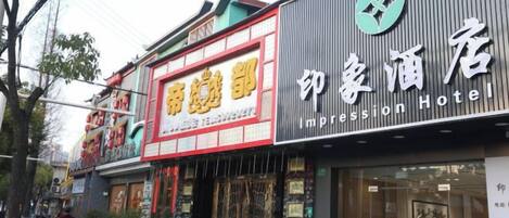 A hotel with a prominent sign for 'Impression Hotel' and another sign for 'House of Beauty'.