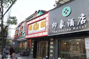 Un hotel con un letrero destacado que dice 'Impression Hotel' y otro letrero que dice 'House of Beauty'.