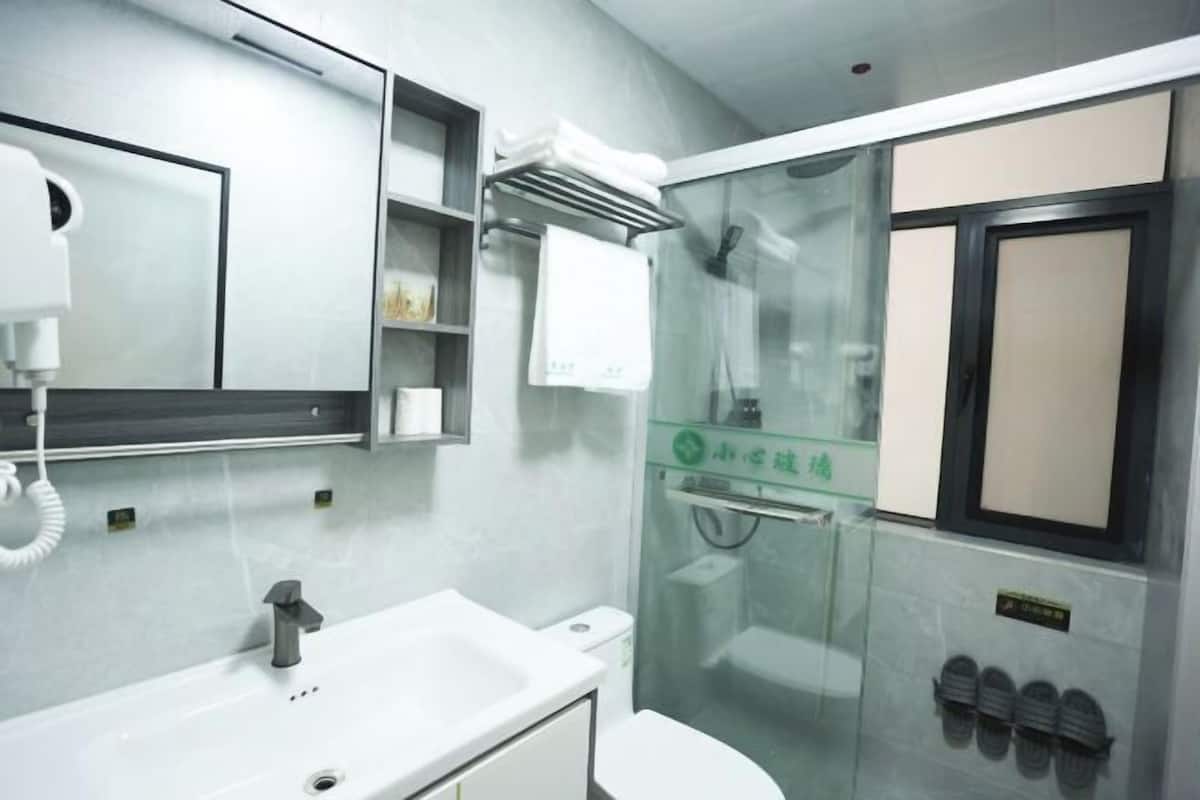 Um banheiro moderno com pia branca, espelho, box de vidro e vaso sanitário.