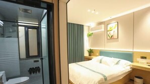 A modern hotel room with a bed, bedside table, and a small potted plant. - Shanghai Xinnuo Hotel (Shanghai)