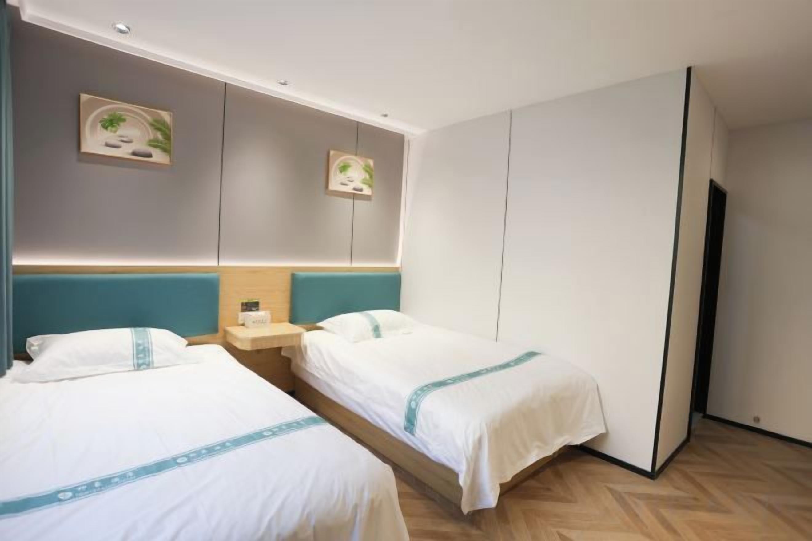 A hotel room with two beds, a nightstand, and a wardrobe.
