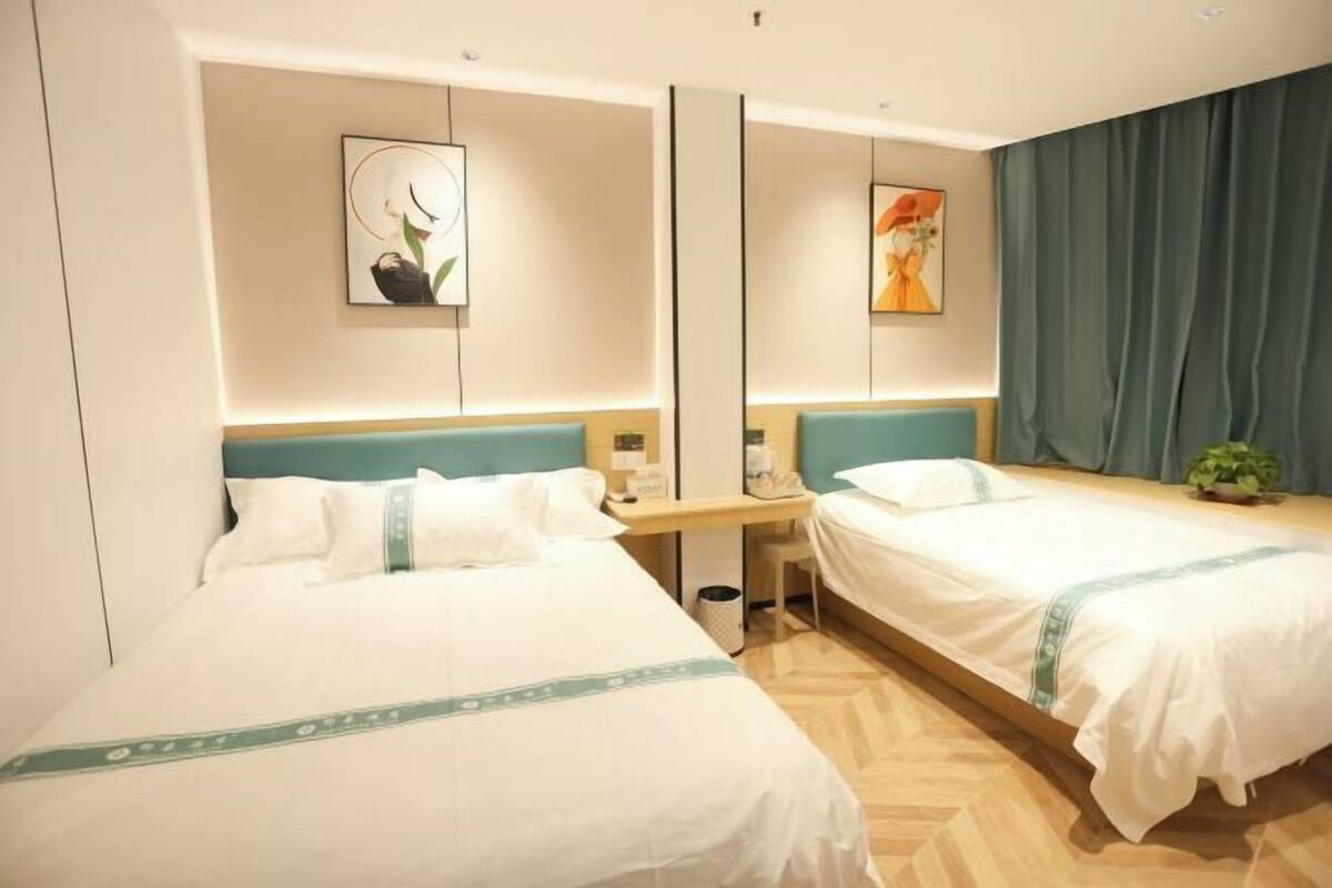 Quarto de hotel com duas camas, uma escrivaninha, um espelho e obras de arte nas paredes.