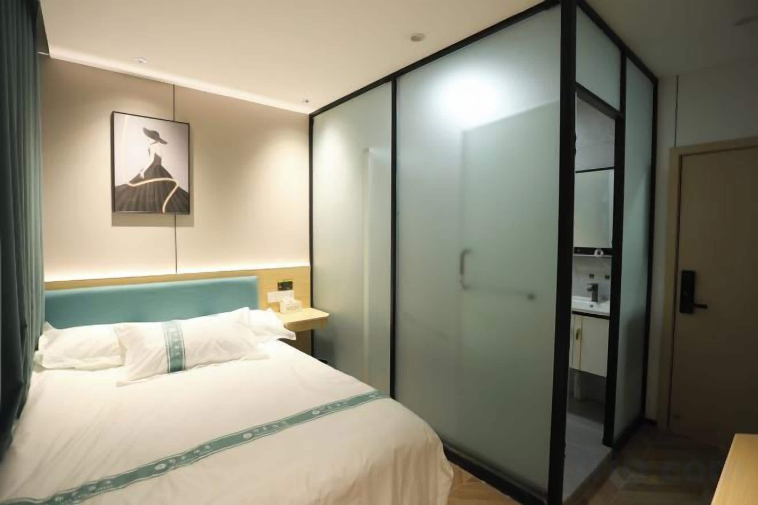 Una habitación de hotel con una cama, una mesita de noche, un armario y un cuadro en la pared.