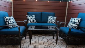 Eine Terrassenfläche mit einer blauen Sofagarnitur, zwei passenden Sesseln und einem kleinen Couchtisch.