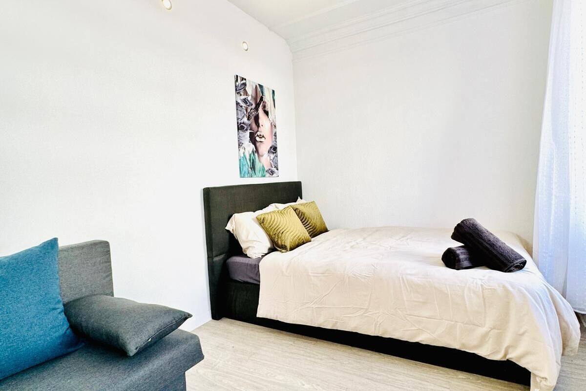 Ein Schlafzimmer mit einem Bett, einem Sofa und einem an der Wand hängenden Bild.