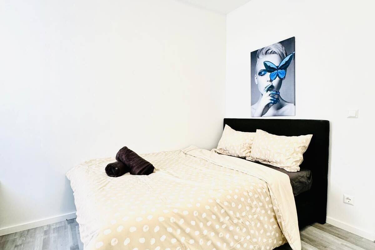 Ein Schlafzimmer mit einem Bett, einem Kopfkissen, einer Decke, einem Bild an der Wand und einer Deckenleuchte.