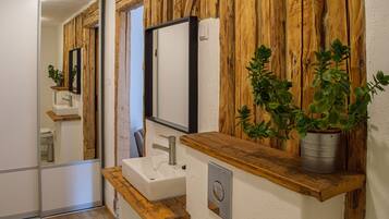 Un baño con pared de madera, lavamanos, espejo y planta en maceta.