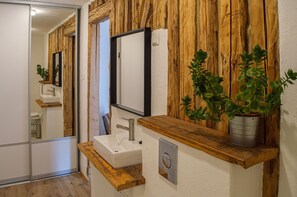 Ein Badezimmer mit Holzwand, Waschbecken, Spiegel und einem Blumentopf.