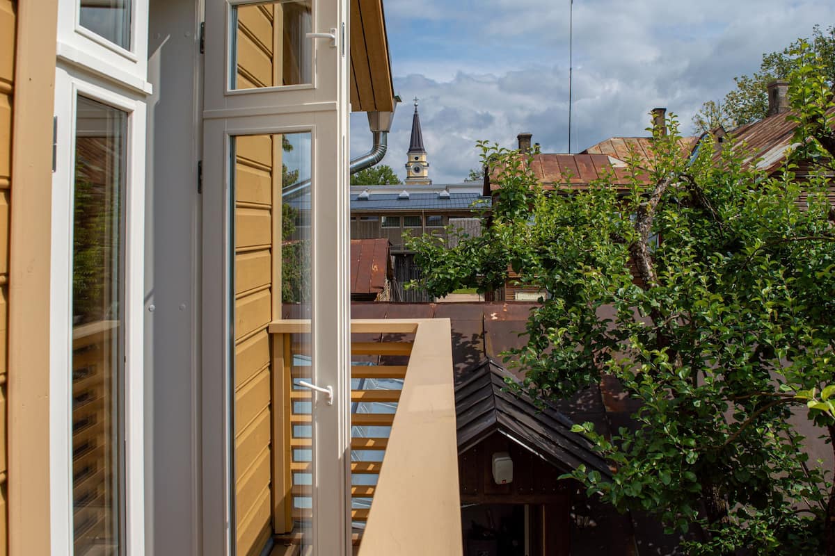 A view from a balcony with a clear sky and a church steeple in the background.